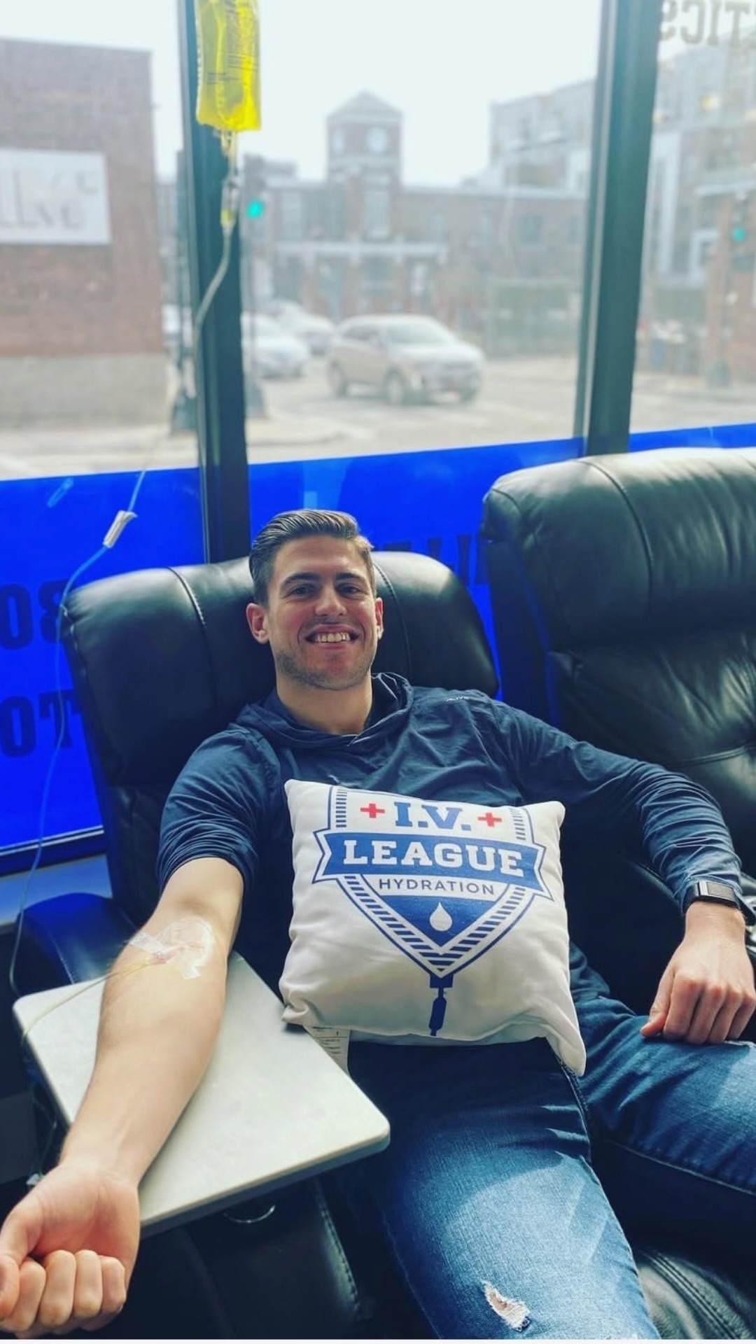 Client receiving an IV drip by the window with an IV League Hydration branded pillow
