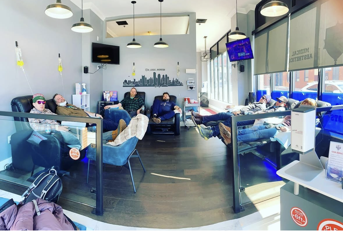 Full hydration lounge with multiple clients receiving IV drips under the Boston skyline wall mural